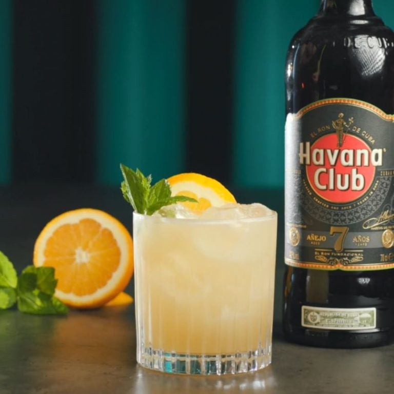 Mai Tai cocktail på et bord med en flaske Havana Club 7 og appelsiner.