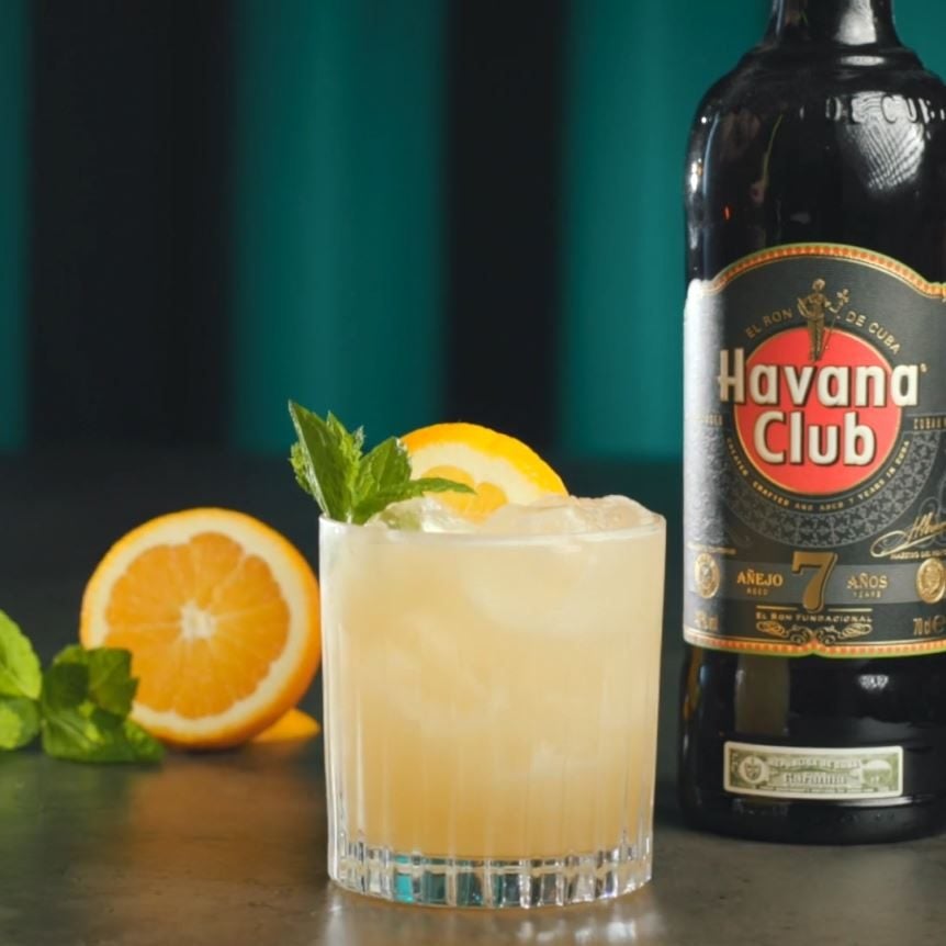 Mai Tai cocktail på et bord med en flaske Havana Club 7 og appelsiner.