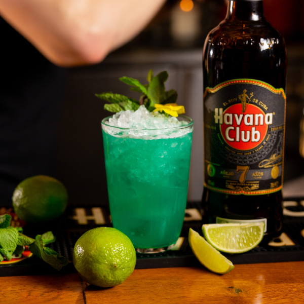 En Havana club rom 7 års flaske, og en blå drink på et bord.
