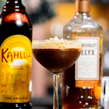 A kind of coffee cocktail på et bord med en flaske Kahlúa og en flaske Absolut Elyx Vodka.