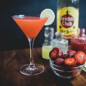 A Strawberry Daiquiri cocktail on a table with a bottle of Havana Club 3 year old rum