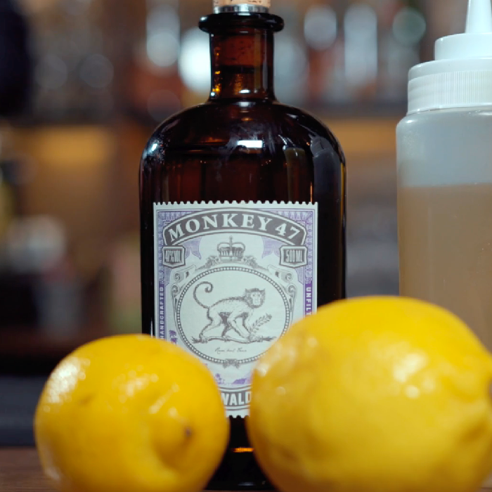 En flaske Monkey 47 på et bord med citroner