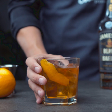 Old fashioned drink på et bord med en flaske Jameson Whiskey Black Barrel og en appelsin.