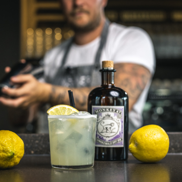 Eldeflower Sour cocktail på et bord med en flaske Monkey 47 Dry Gin