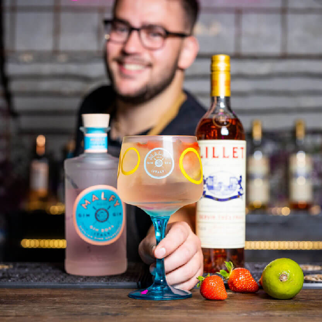 Rosa Rosé drink på et bord med en flaske Malfy Gin Rosa og Lillet Rosé