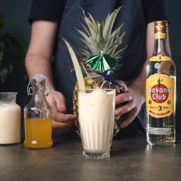 En klassisk Cuban Pina Colada cocktail på et bord med en flaske Havana Club 3 års.