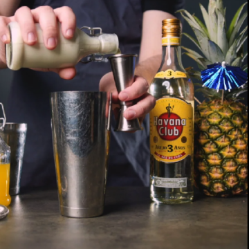 En klassisk Cuban Pina Colada cocktail på et bord med en flaske Havana Club 3 års.