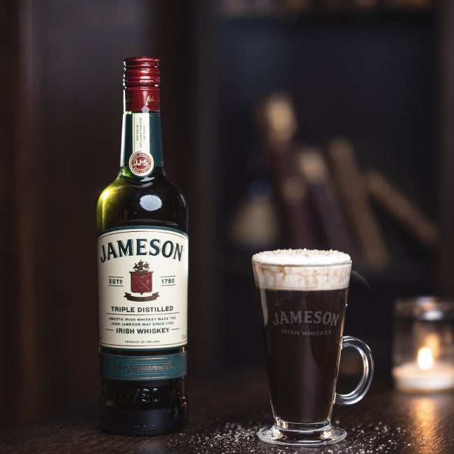 Irish Coffee på et bord med en flaske Jameson Irish Whiskey