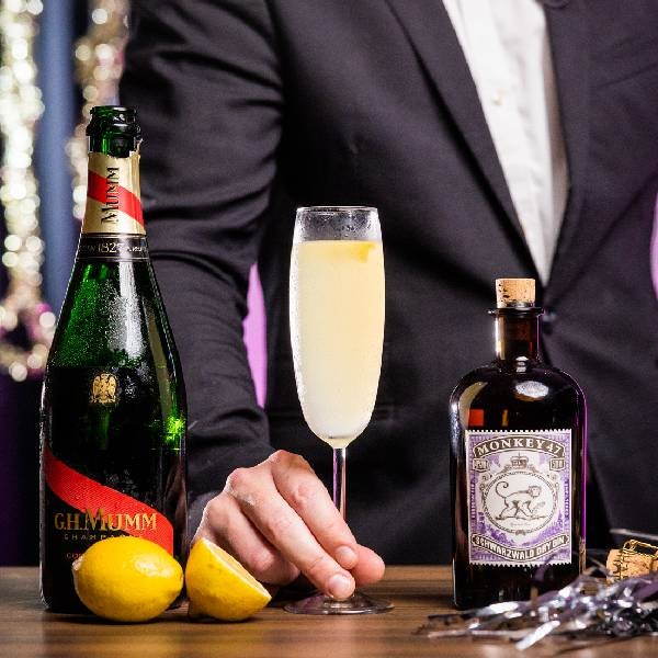 French 75 cocktail på et nytårsbord. En flaske G.H. Mumm Cordon Rouge Brut champagne og en flaske Monkey 47 Dry Gin.