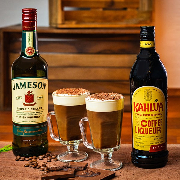 2 Irish Coffee med Kahlúa drinks på et spækbræt. En flaske Jameson Irish Whiskey og en flaske Kahlúa.