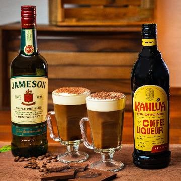 2 Irish Coffee med Kahlúa drinks på et spækbræt. En flaske Jameson Irish Whiskey og en flaske Kahlúa.