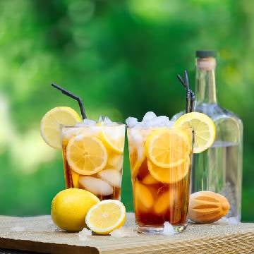 2 Long Island Iced Tea Cocktails på et bord med citroner