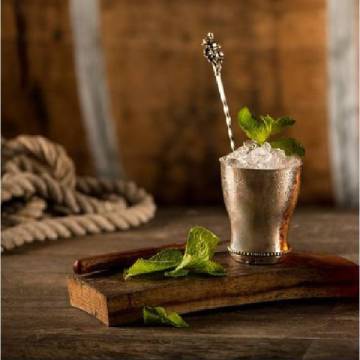 Mint Julep cocktail på et skærebræt med mynteblade.