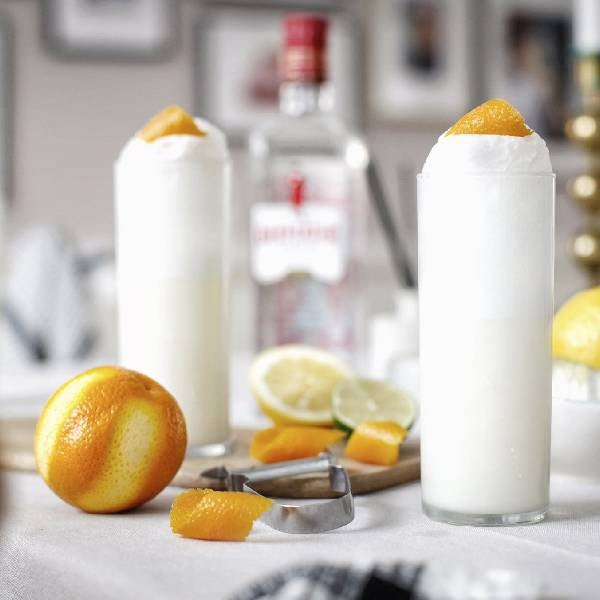 2 Ramos Gin Fizz cocktails på et bord med en flaske Beefeater London Dry Gin.