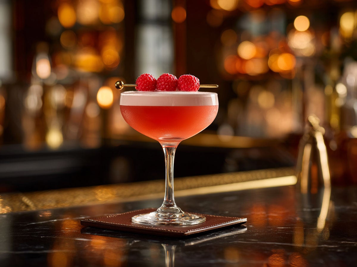 A pink cocktail garnished with raspberries, placed on a barcounter. Created by AI. Edited by Pernod Ricard Sweden