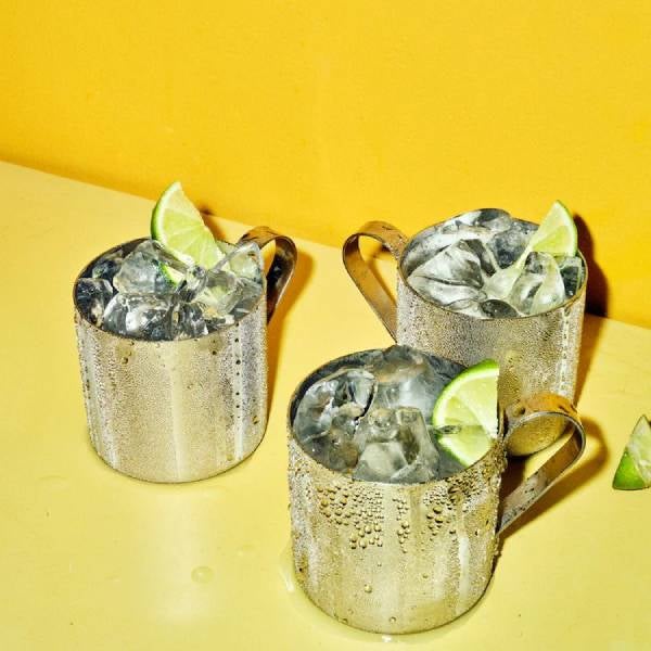 3 Moscow Mule drinks på et gult bord.