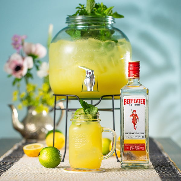 En Tropic Tom Collins punch lavet i en punchbowle. En flaske Beefeater Gin og en buket blomster.