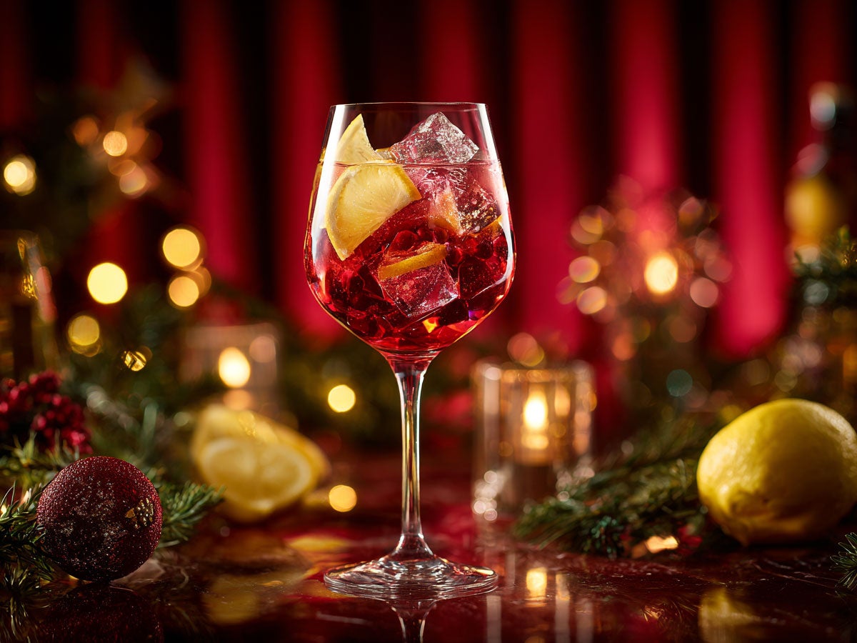 A bright red spritz served in a wineglass with christmas decorations in the background. Created by AI. Edited by Pernod Ricard Sweden