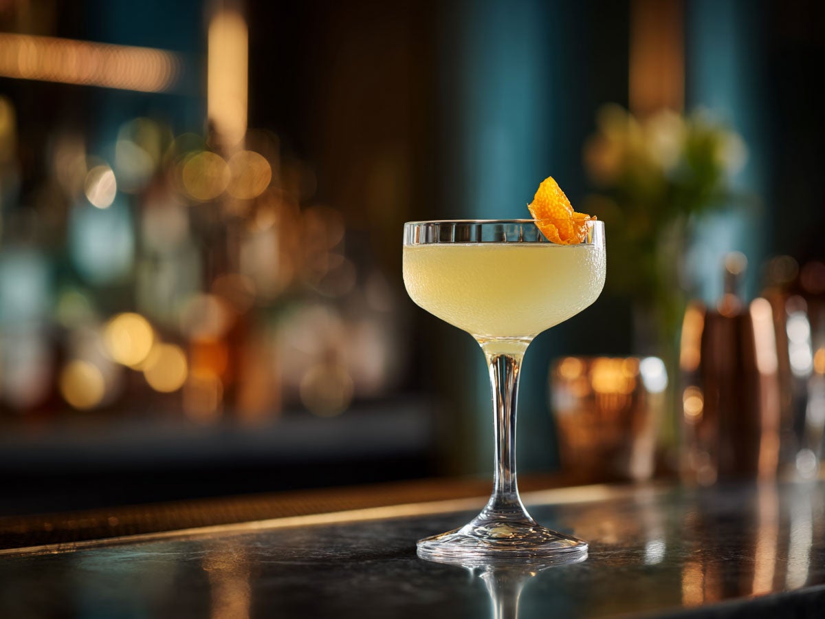 A bright yellow kumquatini drink served in champagne glass. Created by AI. Edited by Pernod Ricard Sweden