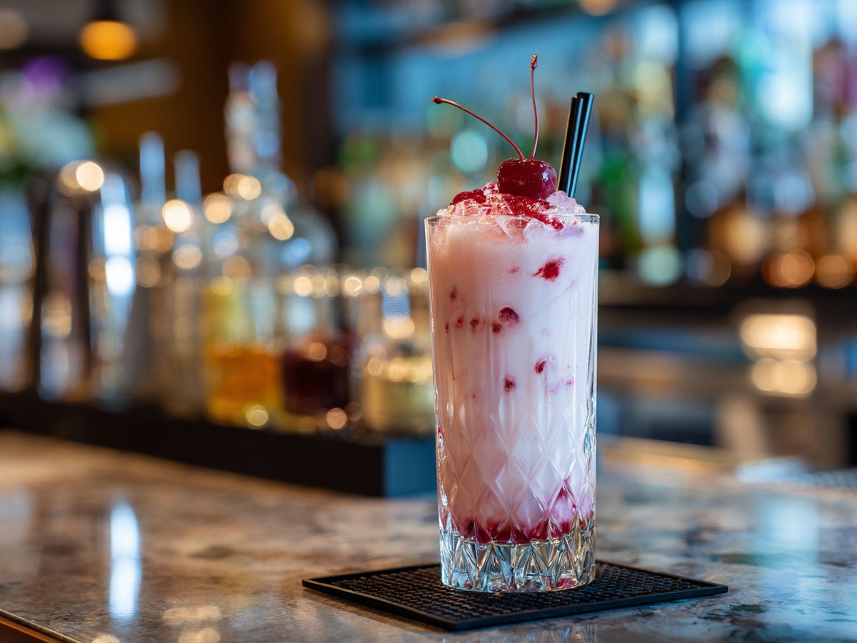 A milk based drink with cherry sauce and a cherry on top. Created by AI. Edited by Pernod Ricard Sweden